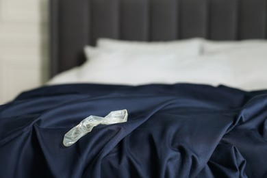 Photo of Unrolled condom on bed in bedroom. Safe sex
