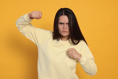 Photo of Young woman ready to fight on orange background