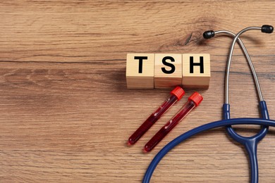 Photo of Endocrinology. Stethoscope, cubes with thyroid hormones and blood samples in test tubes on wooden table. Space for text