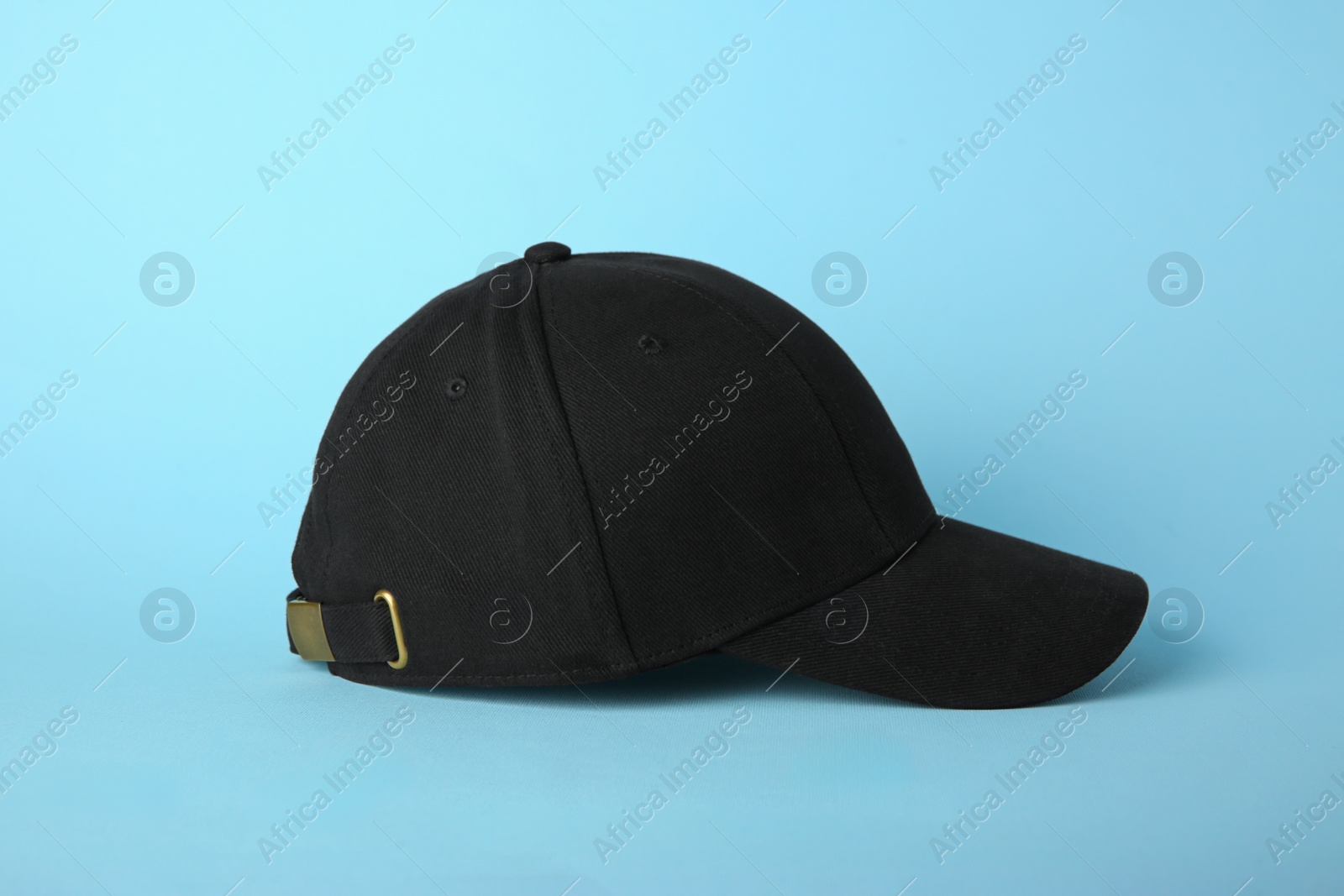 Photo of Stylish black baseball cap on light blue background