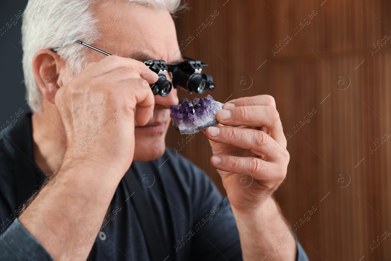 Photo of Male jeweler evaluating semi precious gemstone in workshop, closeup