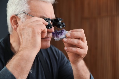 Photo of Male jeweler evaluating semi precious gemstone in workshop, closeup