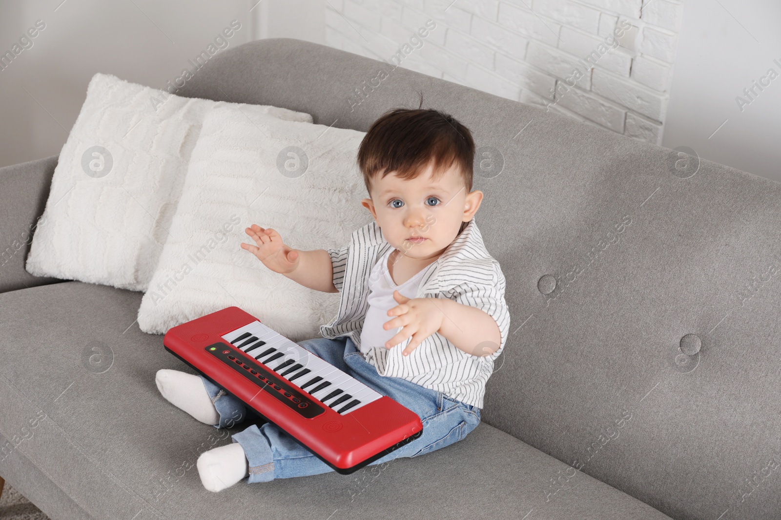 Photo of Cute little boy with toy piano at home