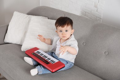 Photo of Cute little boy with toy piano at home