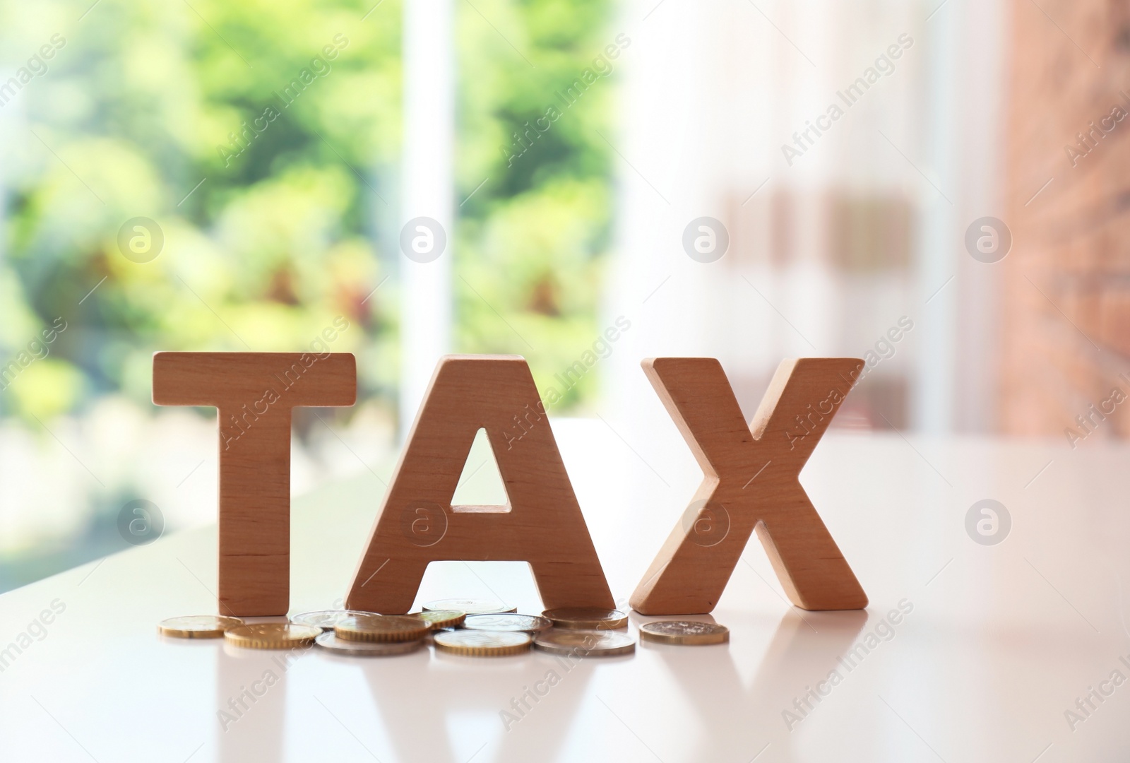 Photo of Word TAX made of letters and coins on table against blurred background