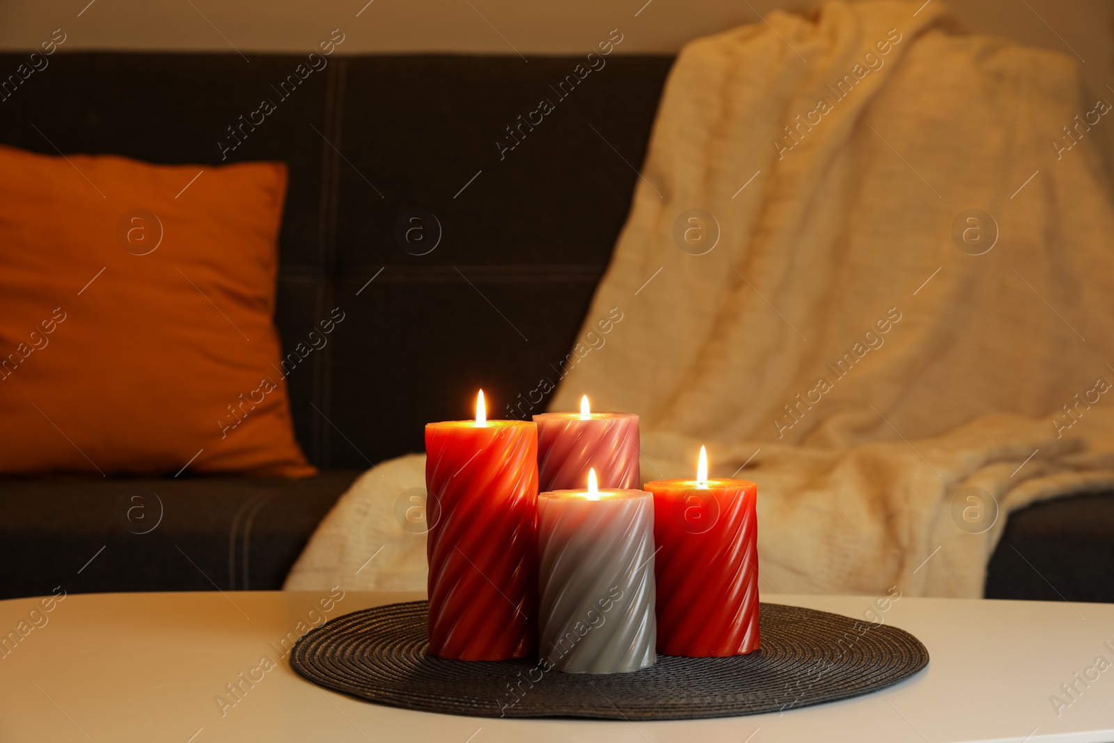 Photo of Burning candles on white table indoors. Cosy atmosphere