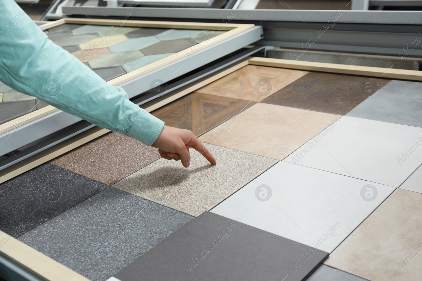 Photo of Man choosing tile among different samples in store, closeup