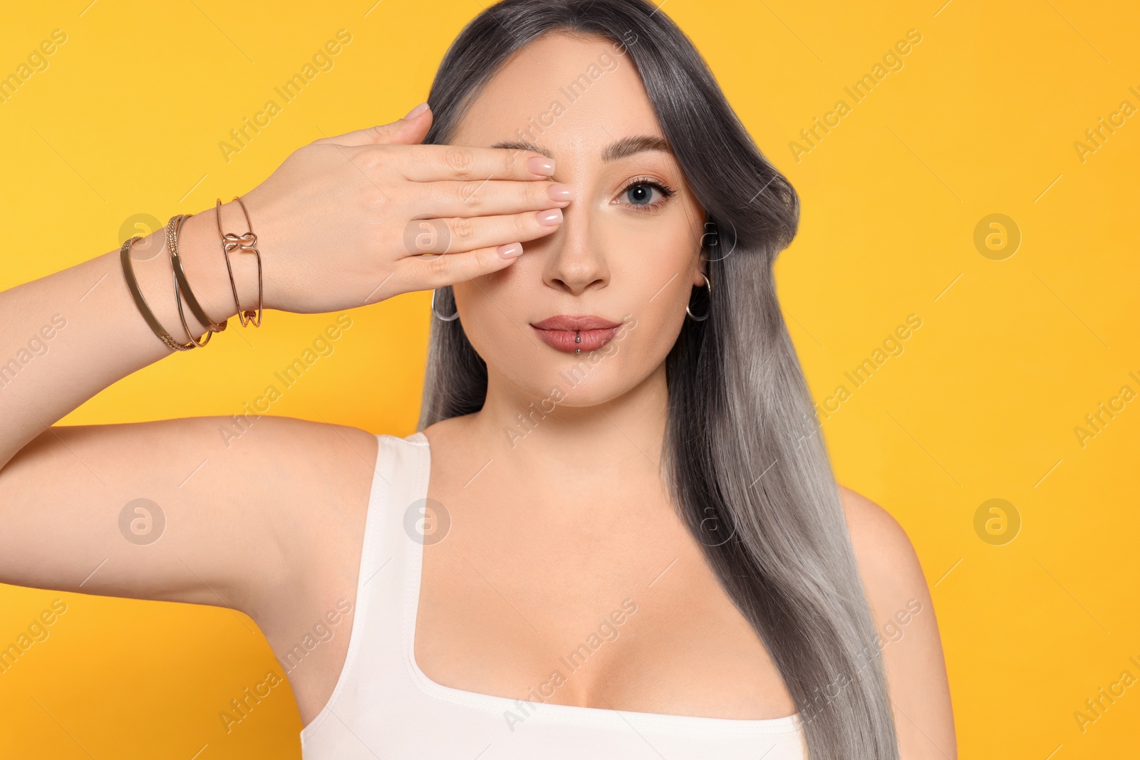 Image of Portrait of beautiful woman with ash hair color on orange background