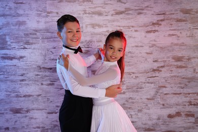 Photo of Beautifully dressed couple of kids dancing together in studio