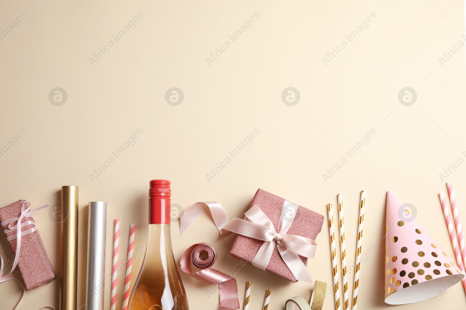 Photo of Creative flat lay composition with bottle of champagne and party accessories on color background. Space for text