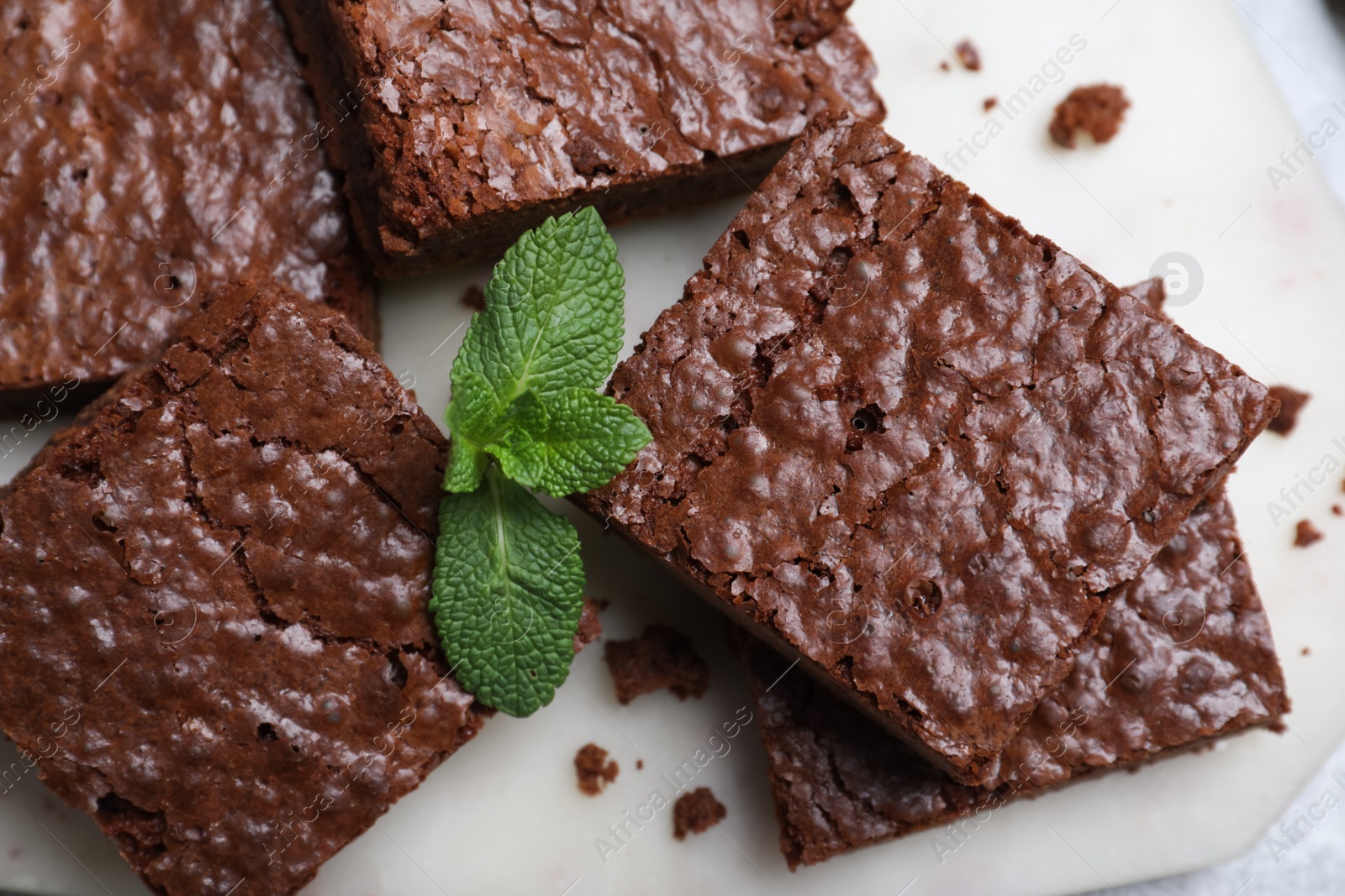 Photo of Delicious chocolate brownies with fresh mint on marble board, top view