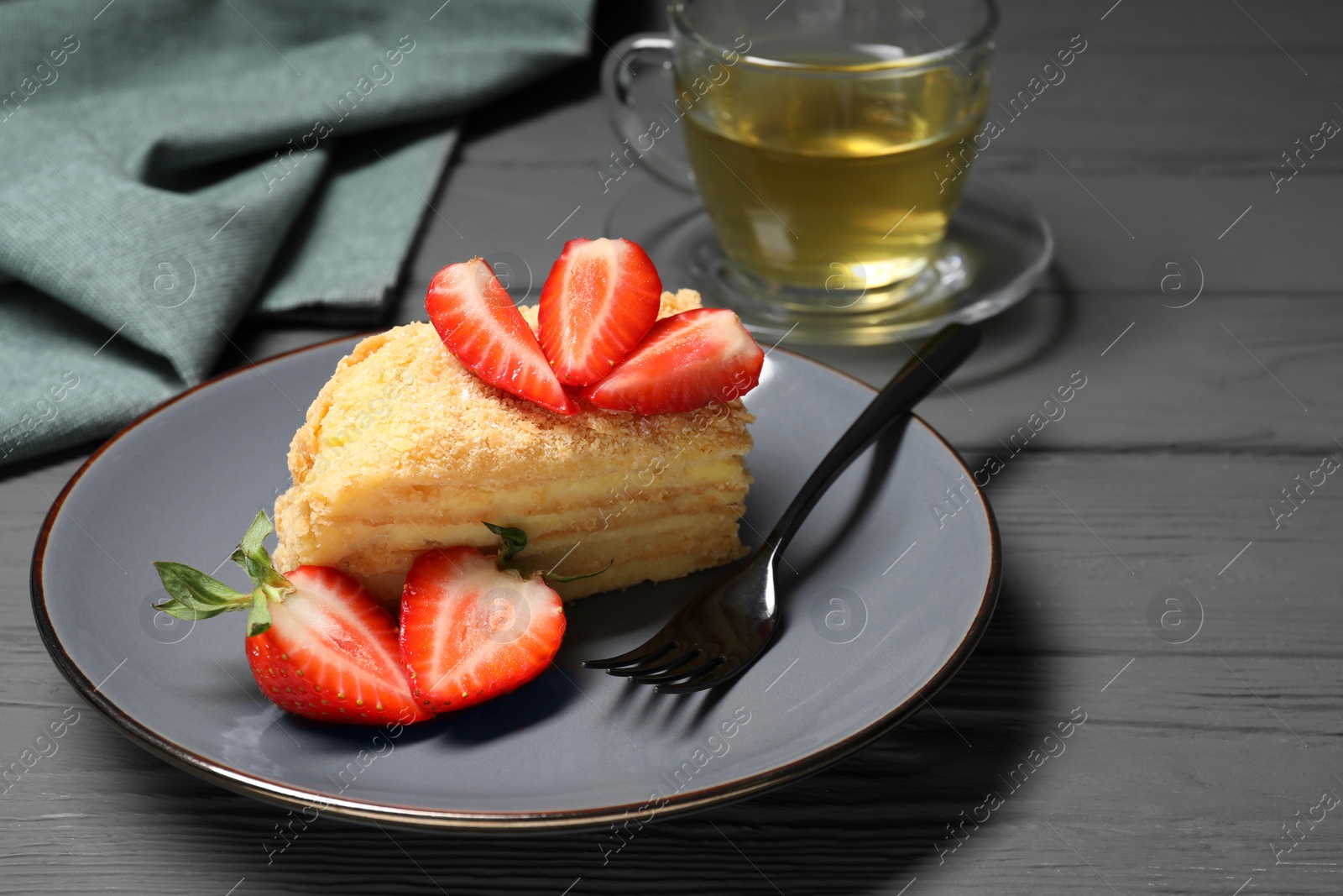 Photo of Piece of delicious Napoleon cake with strawberries on grey wooden table. Space for text