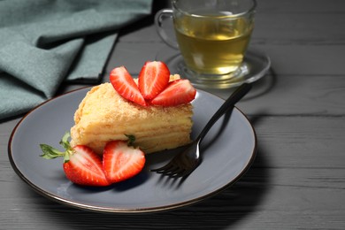 Photo of Piece of delicious Napoleon cake with strawberries on grey wooden table. Space for text