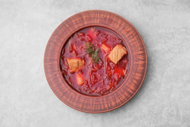 Bowl of delicious borscht on light grey table, top view