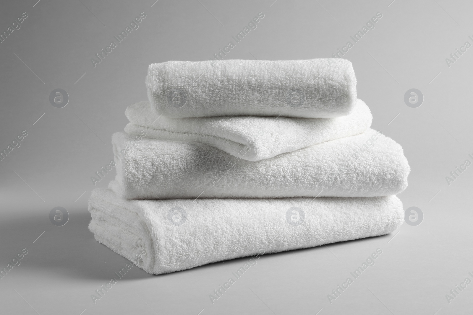 Photo of Stack of fresh towels on light background