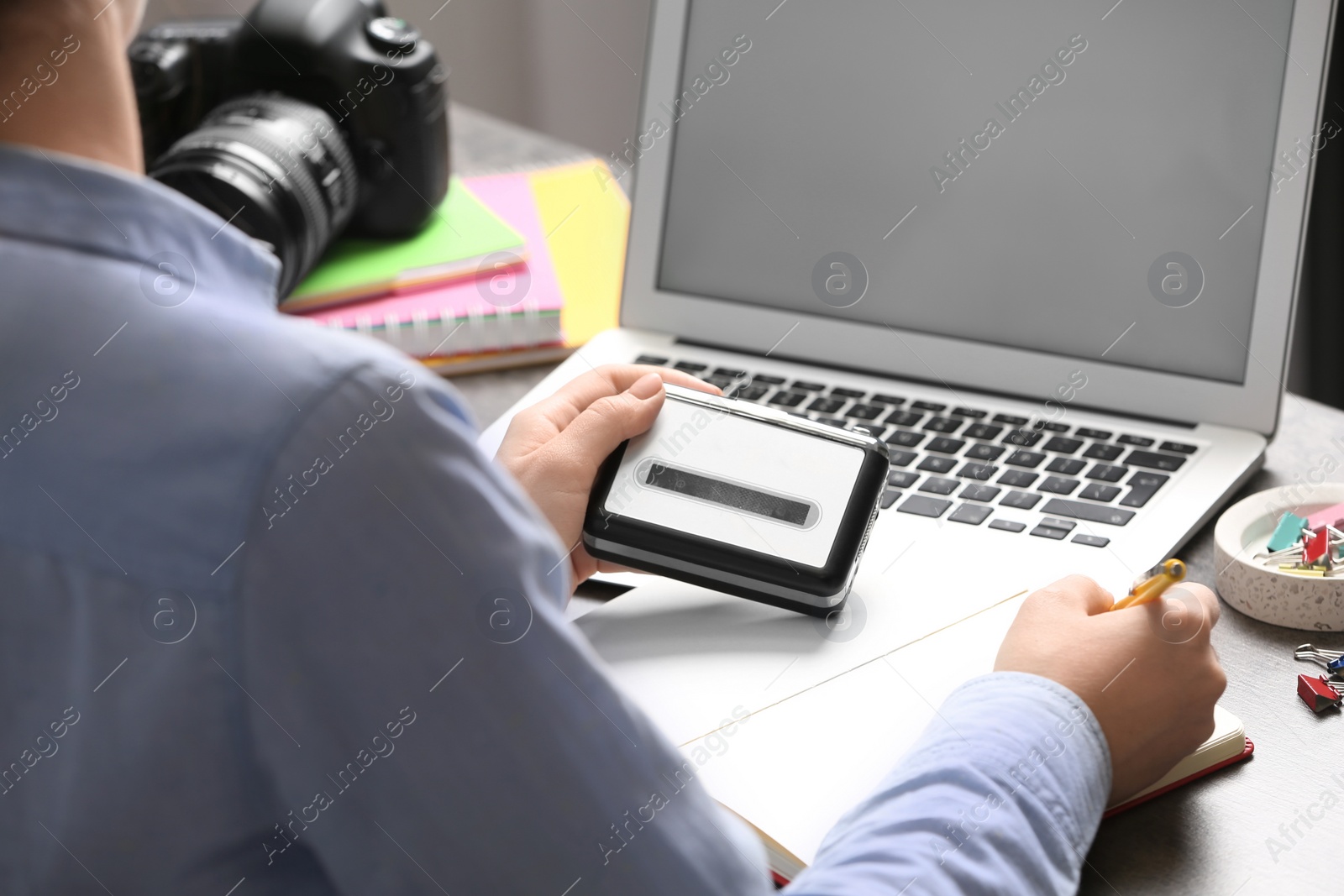 Photo of Journalist with voice recorder working at table in office, closeup