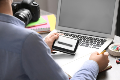 Journalist with voice recorder working at table in office, closeup