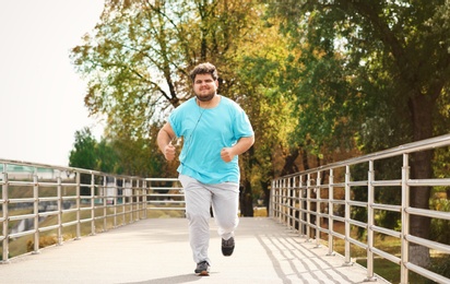 Photo of Young overweight man running outdoors. Fitness lifestyle