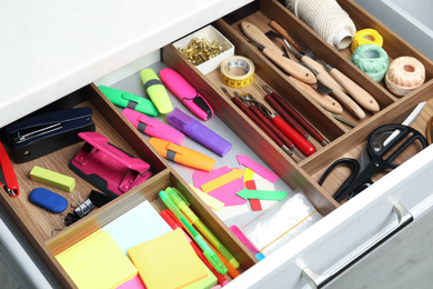 Stationery and sewing accessories in open desk drawer indoors, closeup