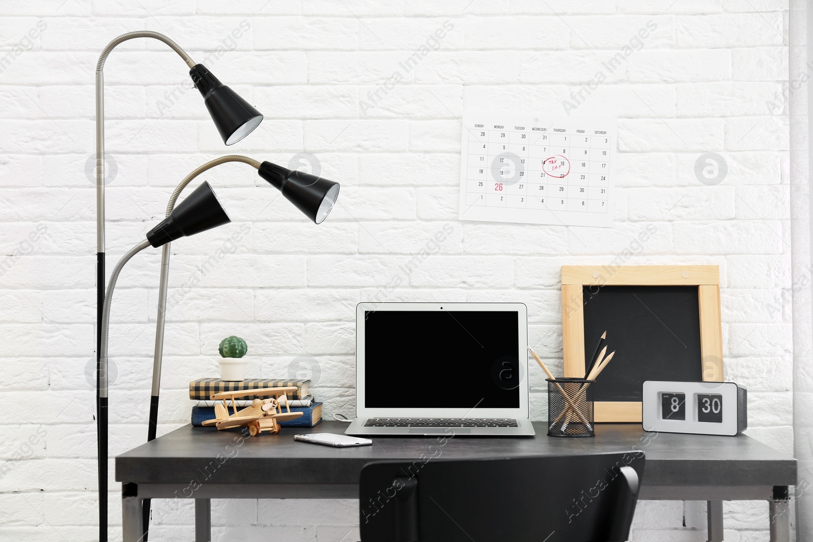 Photo of Stylish workplace with laptop on table near brick wall