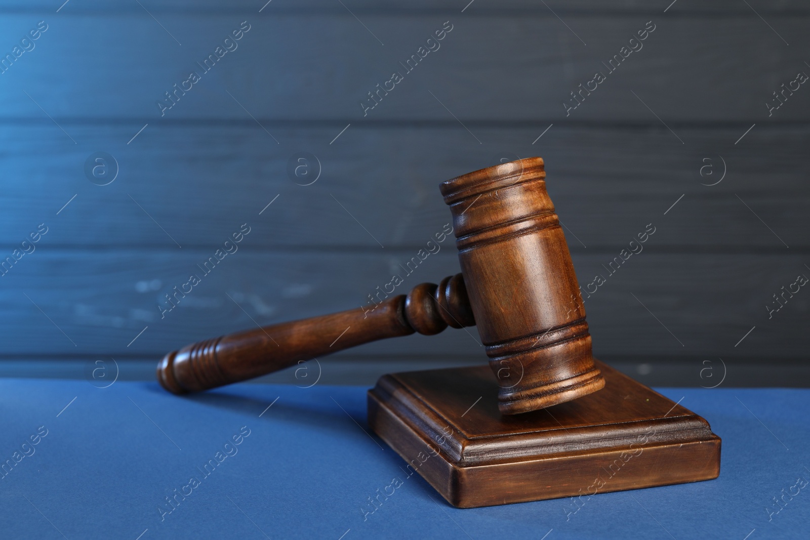 Photo of Wooden gavel and sound block on blue table, closeup