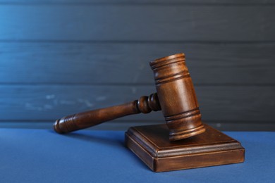 Photo of Wooden gavel and sound block on blue table, closeup