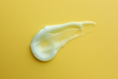 Sample of face cream on yellow background, top view