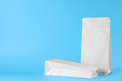 Photo of Two paper bags on light blue background, space for text