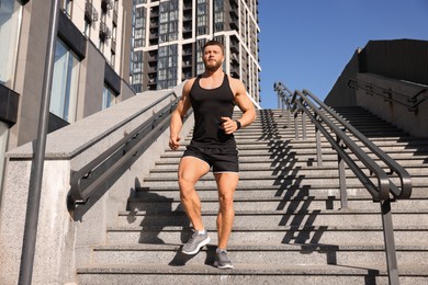 Photo of Man running down stairs outdoors on sunny day, low angle view
