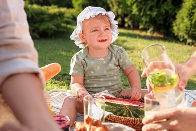 Photo of Cute child and her parents having picnic on sunny day in garden