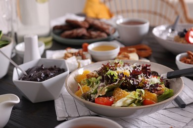 Photo of Delicious salad and many different dishes served on buffet table for brunch