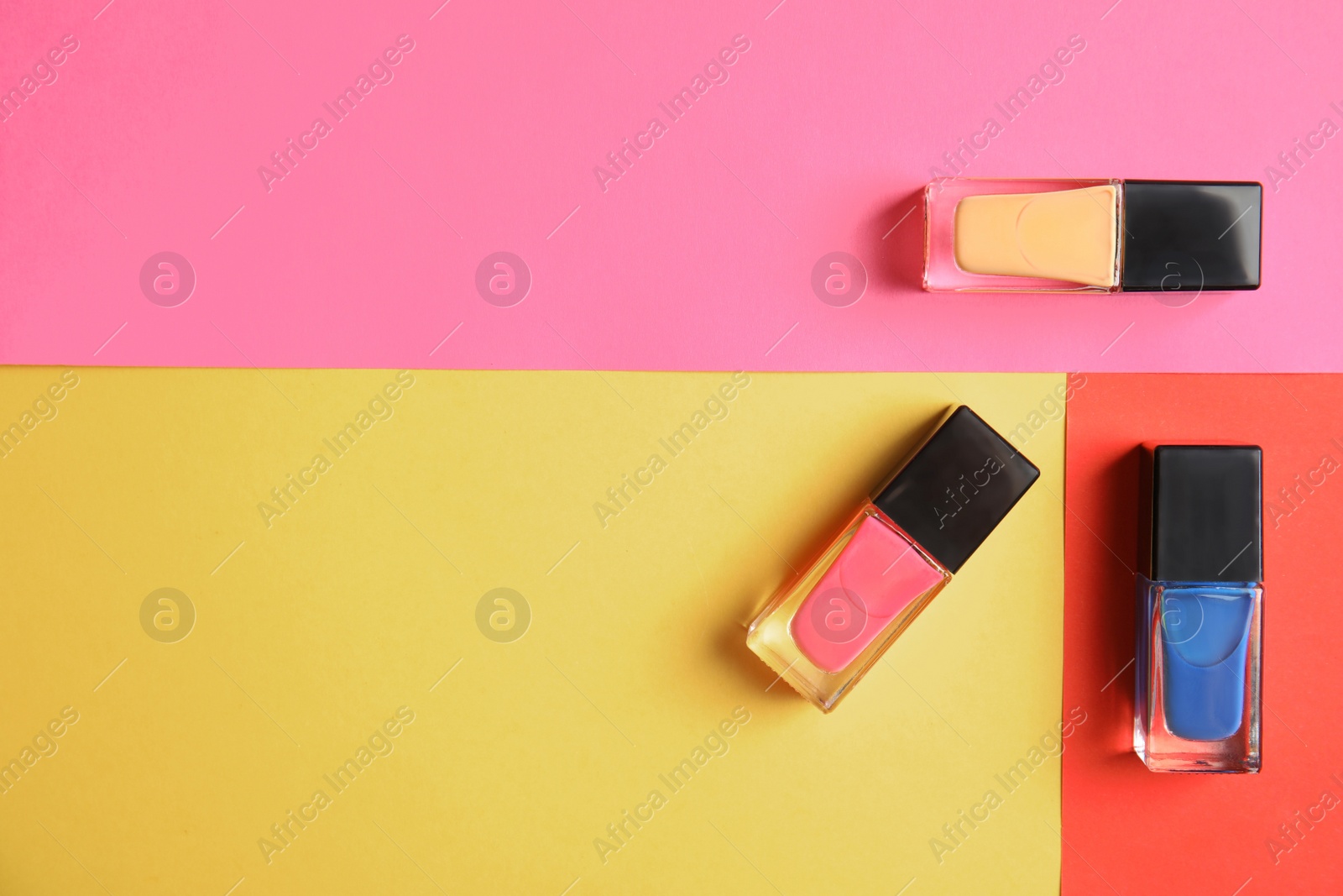 Photo of Bottles of nail polish on color background, top view with space for text