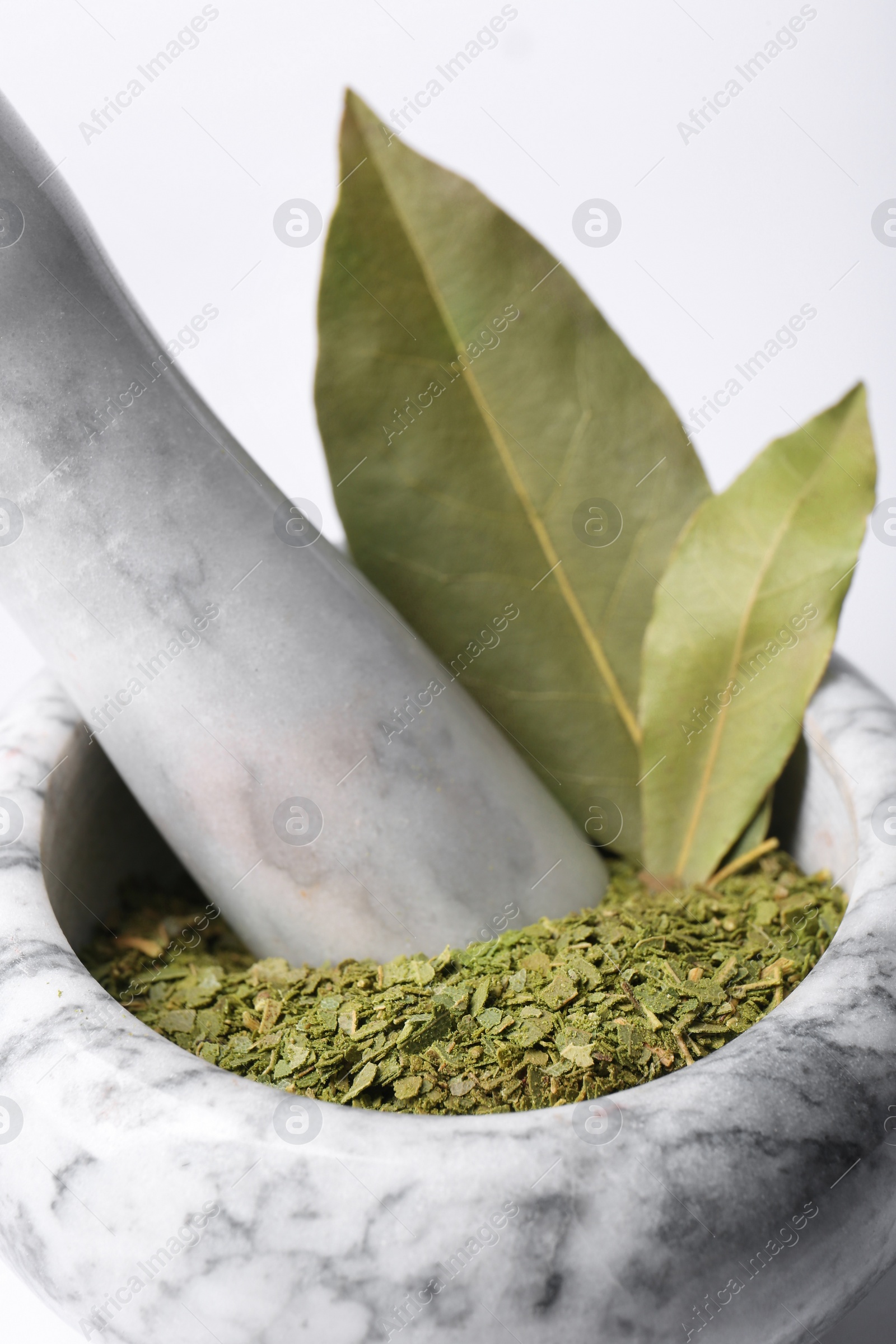 Photo of Marble mortar with whole and ground bay leaves on white background, closeup