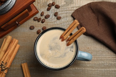 Cup of hot coffee with aromatic cinnamon on wooden table, flat lay