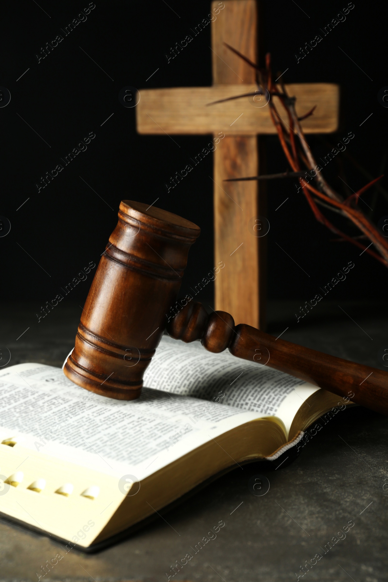 Photo of Judge gavel, bible, wooden cross and crown of thorns on grey table