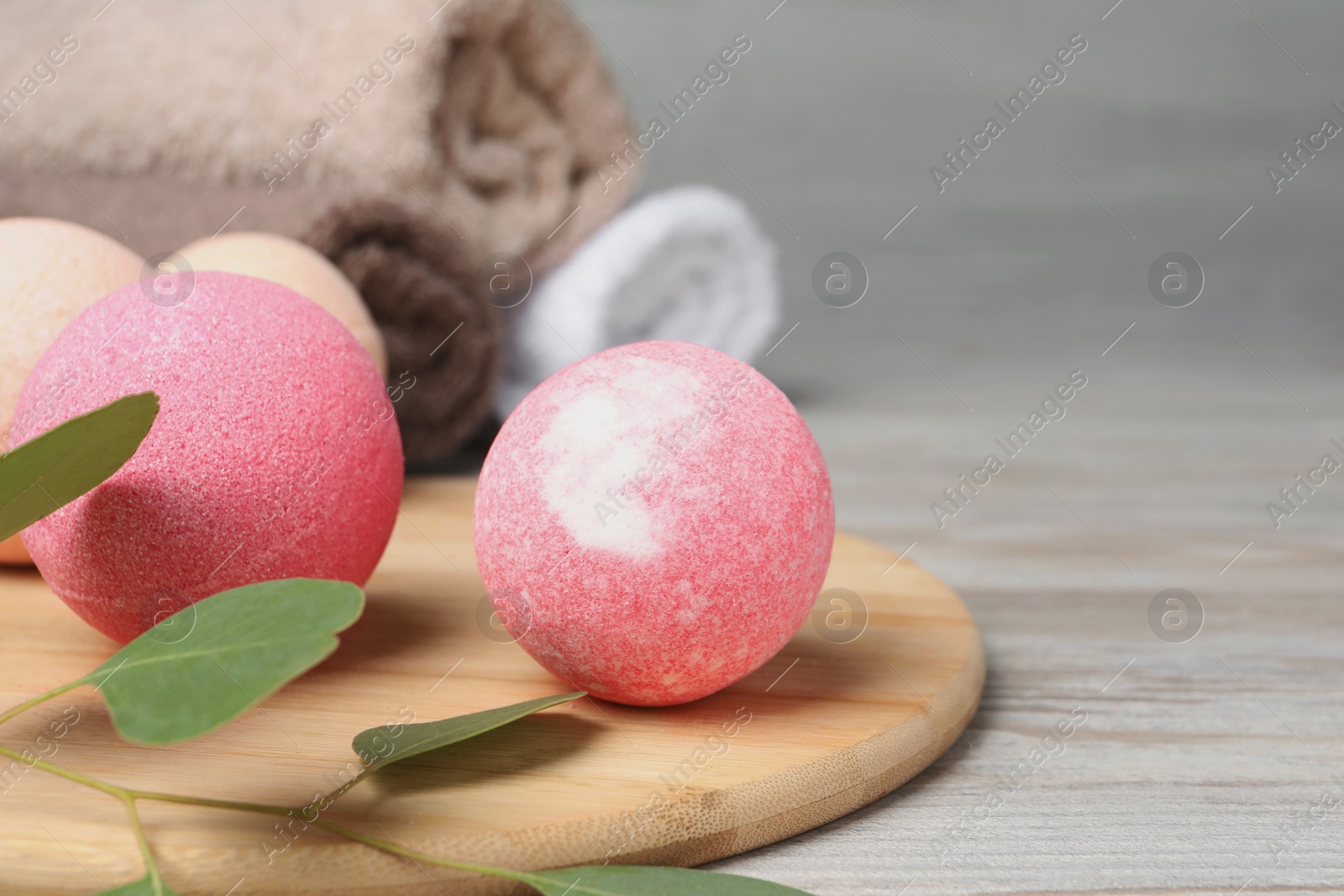 Photo of Beautiful aromatic bath bombs and green branch on light wooden table, closeup. Space for text