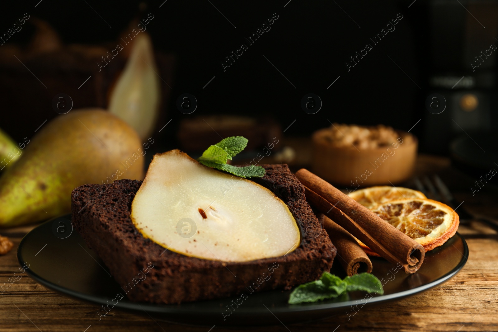 Photo of Tasty pear bread served with mint, cinnamon and dried orange slices on wooden table. Homemade cake