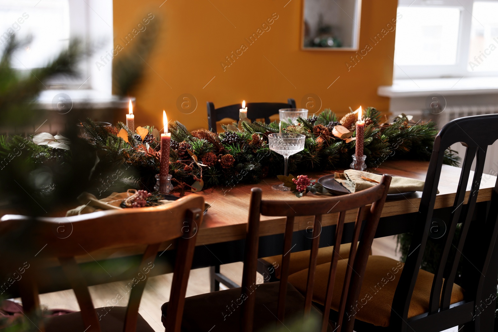 Photo of Dining table with burning candles and Christmas decor in stylish room. Interior design