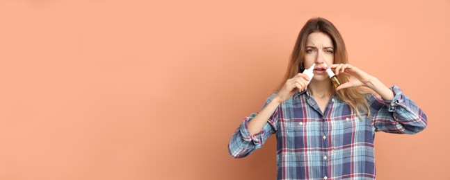 Photo of Sick young woman using nasal sprays on coral background