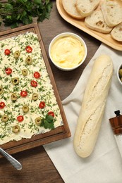 Photo of Fresh natural butter board with cut olives, pepper and bread on wooden table, flat lay