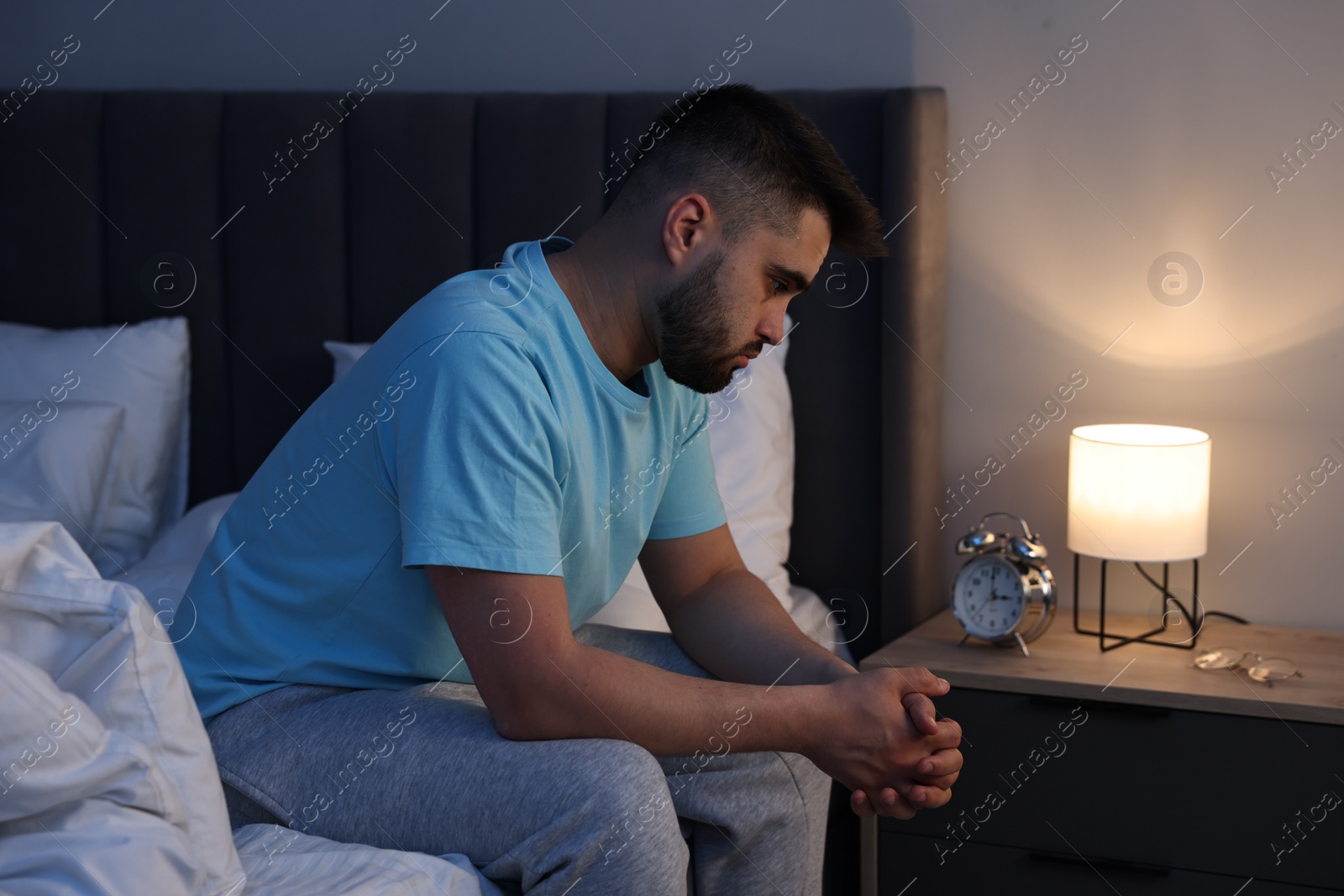 Photo of Frustrated man suffering from insomnia on bed