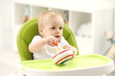 Children toys. Cute little boy playing with spinning top in high chair at home