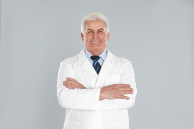 Photo of Happy senior man in lab coat on light grey background