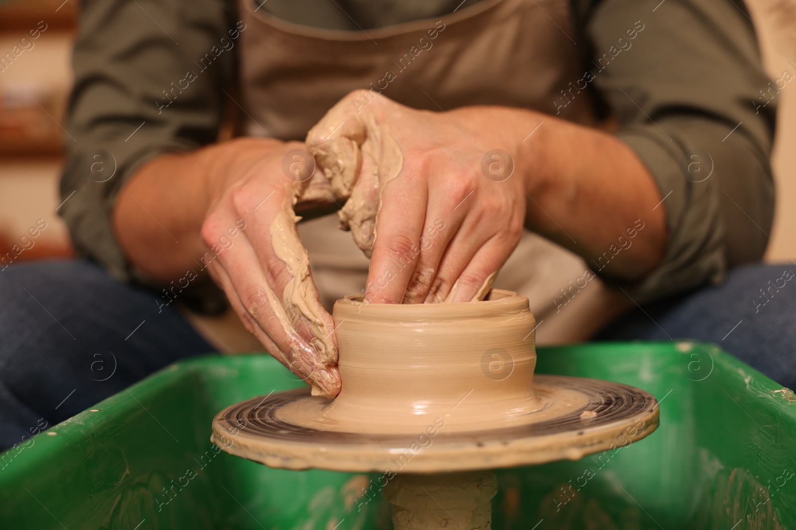 Photo of Clay crafting. Man making bowl on potter's wheel indoors, closeup