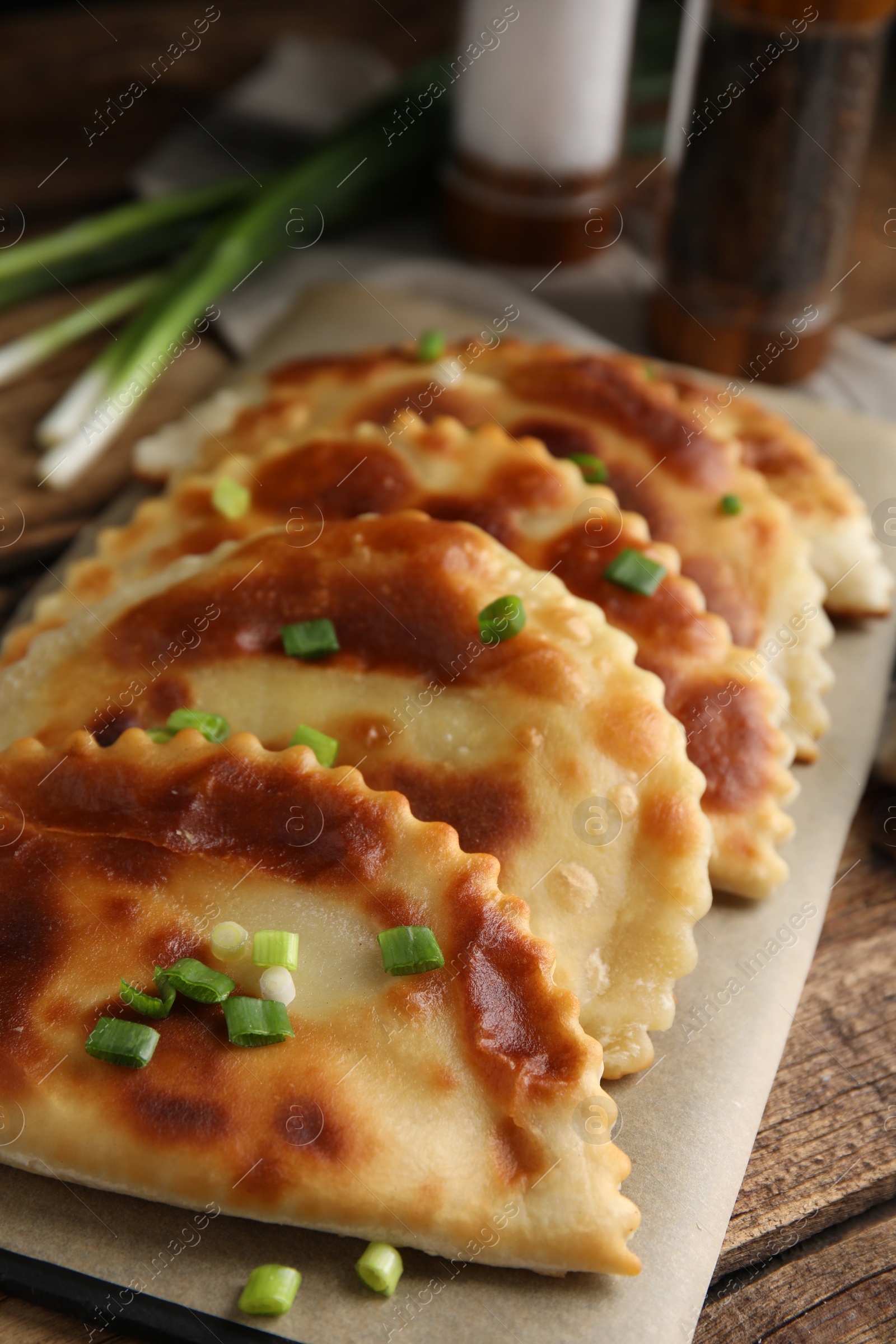 Photo of Board with delicious fried chebureki on wooden table