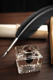 Photo of Feather pen, inkwell and paper roll on wooden table