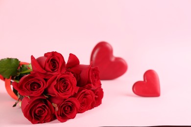 Photo of Beautiful red roses and decorative hearts on pink background, space for text. St. Valentine's day celebration