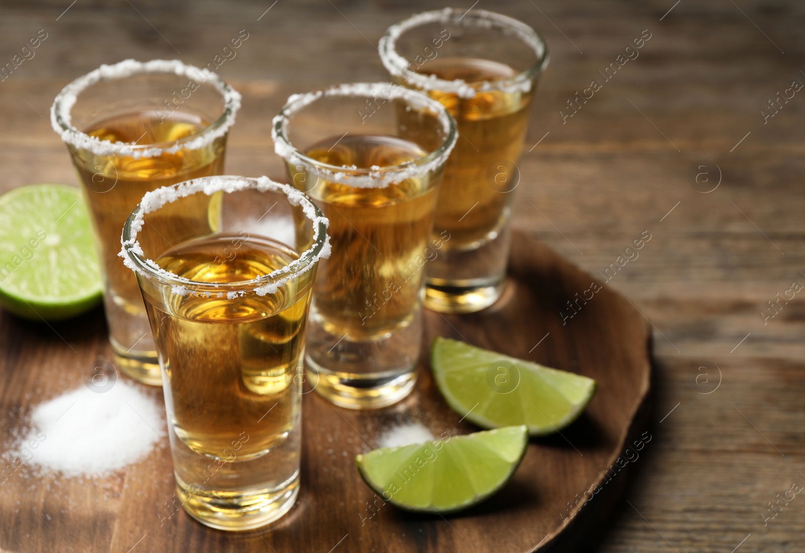 Photo of Mexican Tequila shots, lime and salt on wooden table