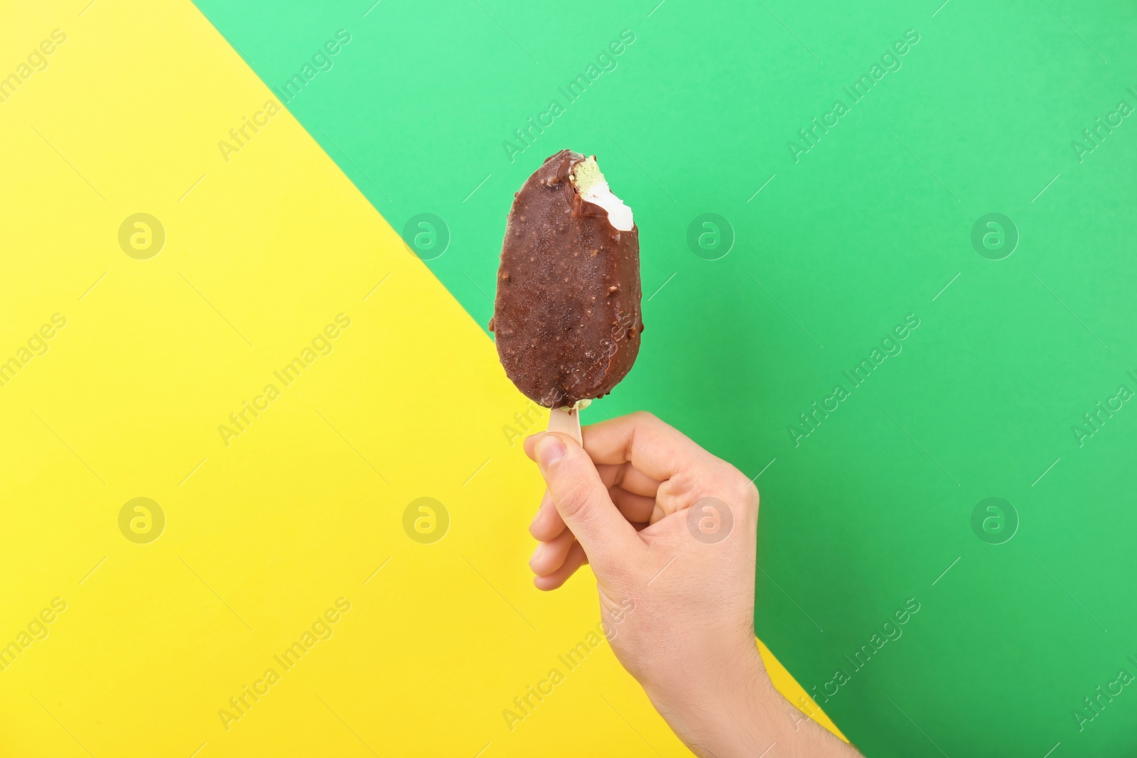 Photo of Man holding yummy ice cream on color background. Focus on hand