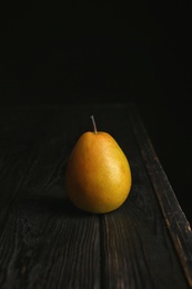 Ripe pear on wooden table against dark background